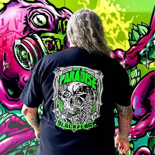Man wearing a black Blackflag t-shirt with hand drawn Rest In Paradise illustration on back.